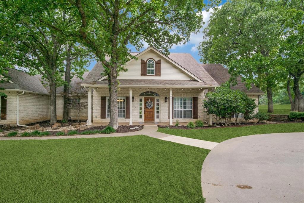 a front view of a house with a garden and trees