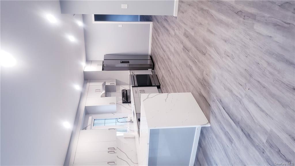 a large white kitchen with wooden floors and stainless steel appliances