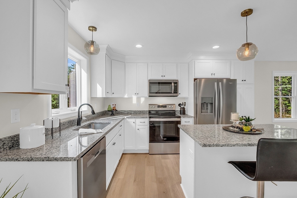 a kitchen with granite countertop a sink stainless steel appliances and white cabinets