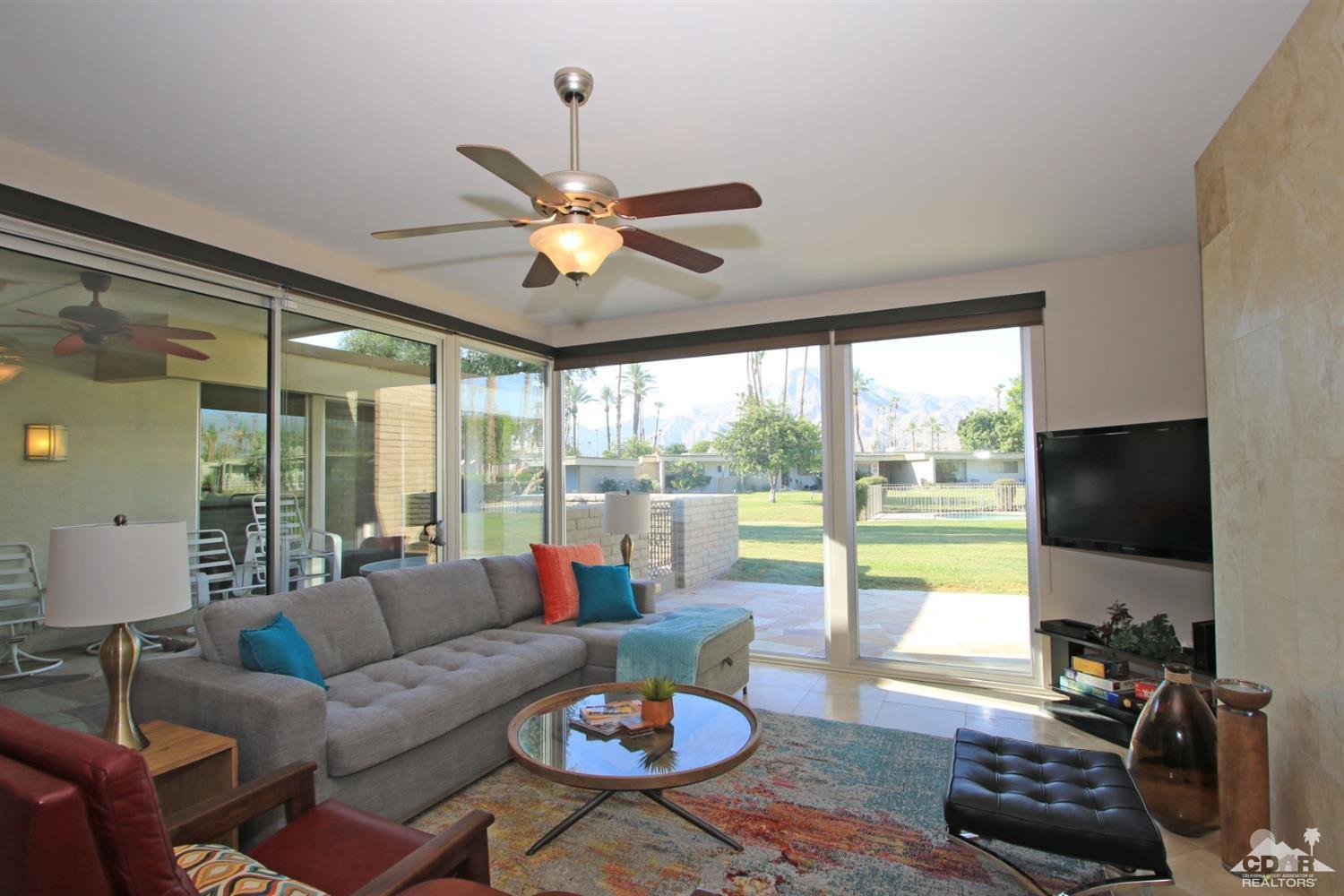 a living room with furniture floor to ceiling window and a flat screen tv