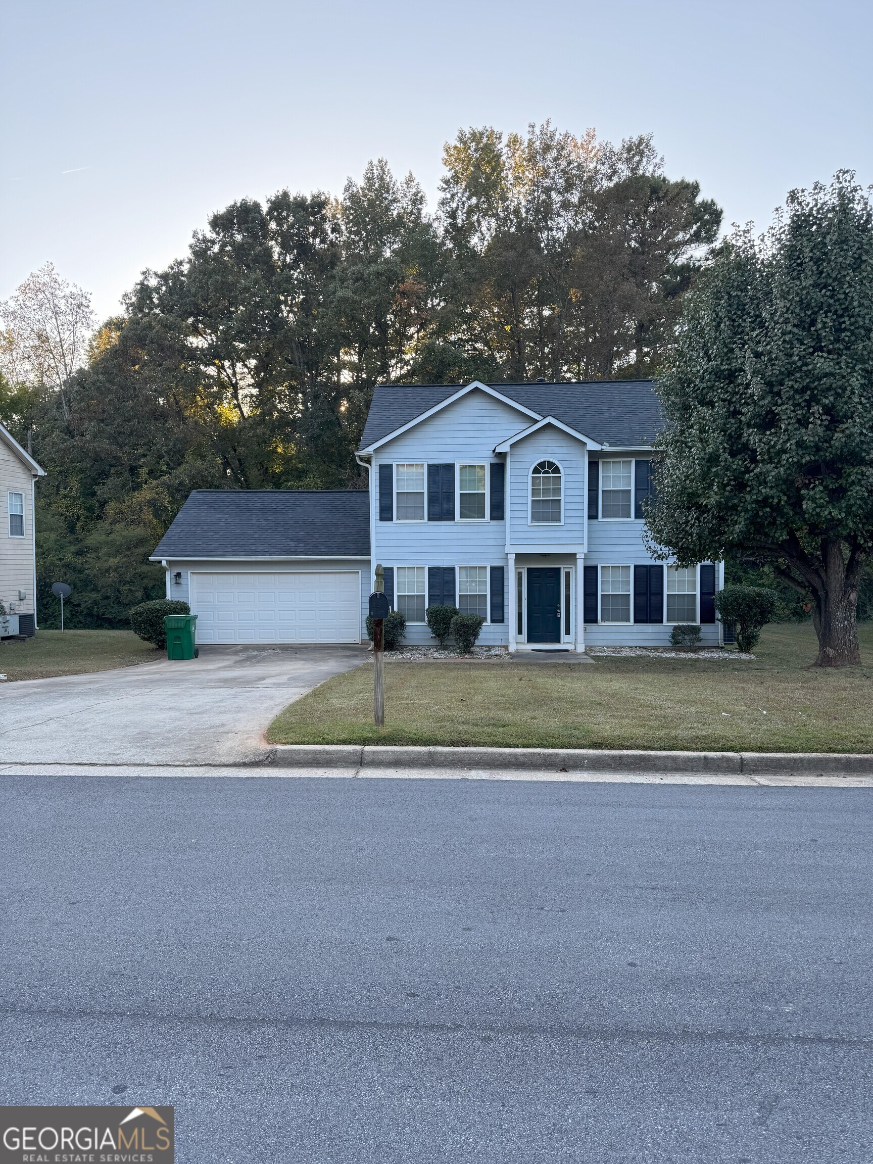 a view of house with a big yard and large trees