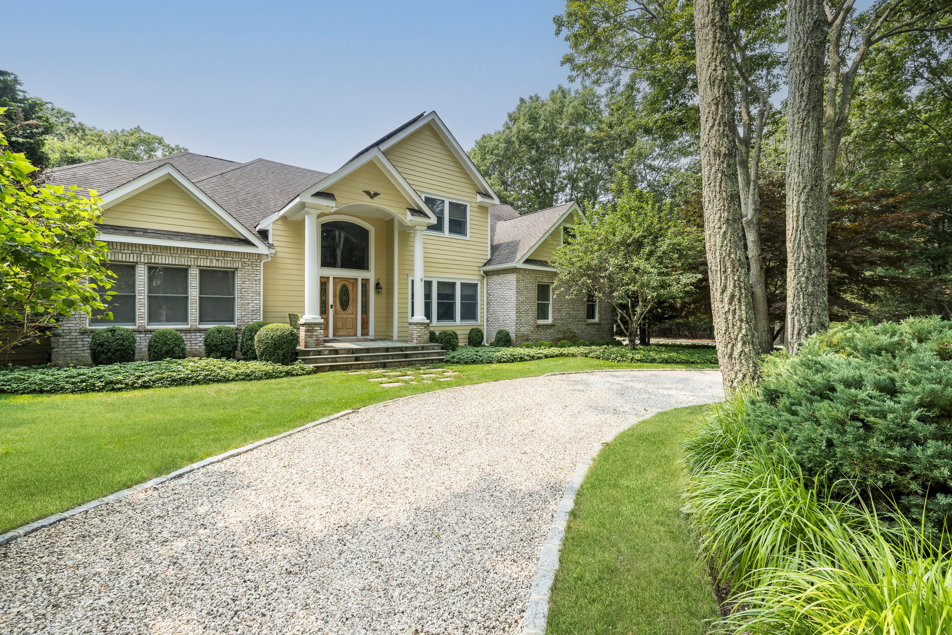 a view of a white house with a big yard and potted plants