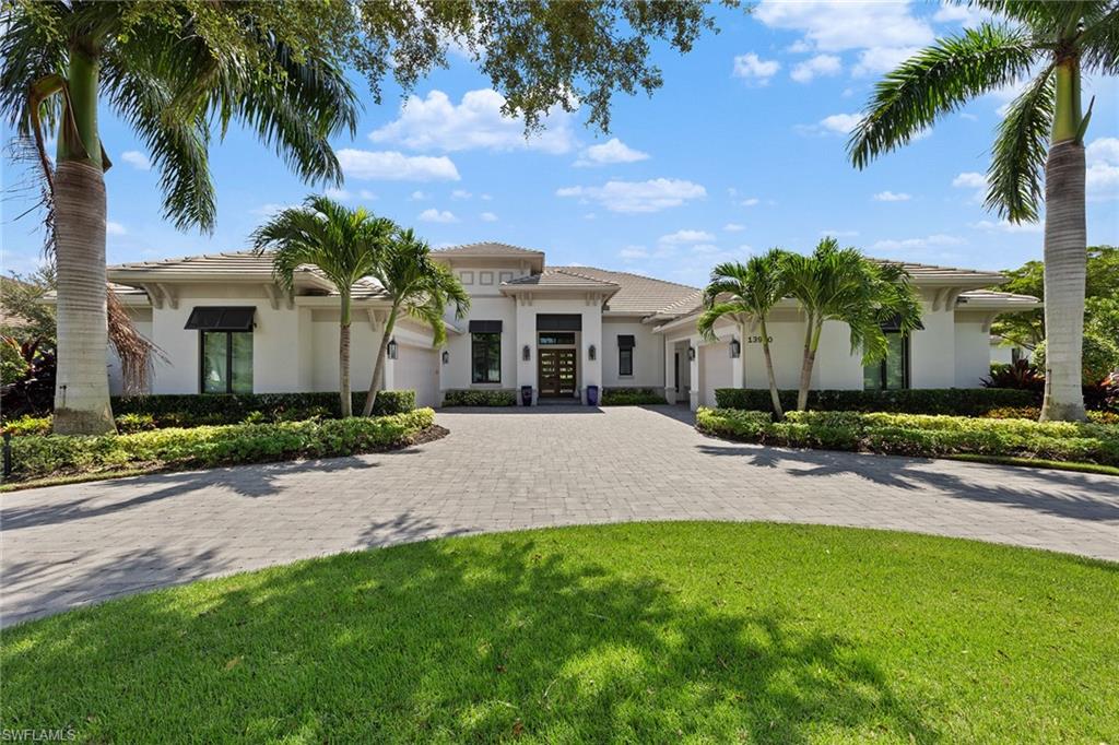 front view of a house with a yard and palm trees