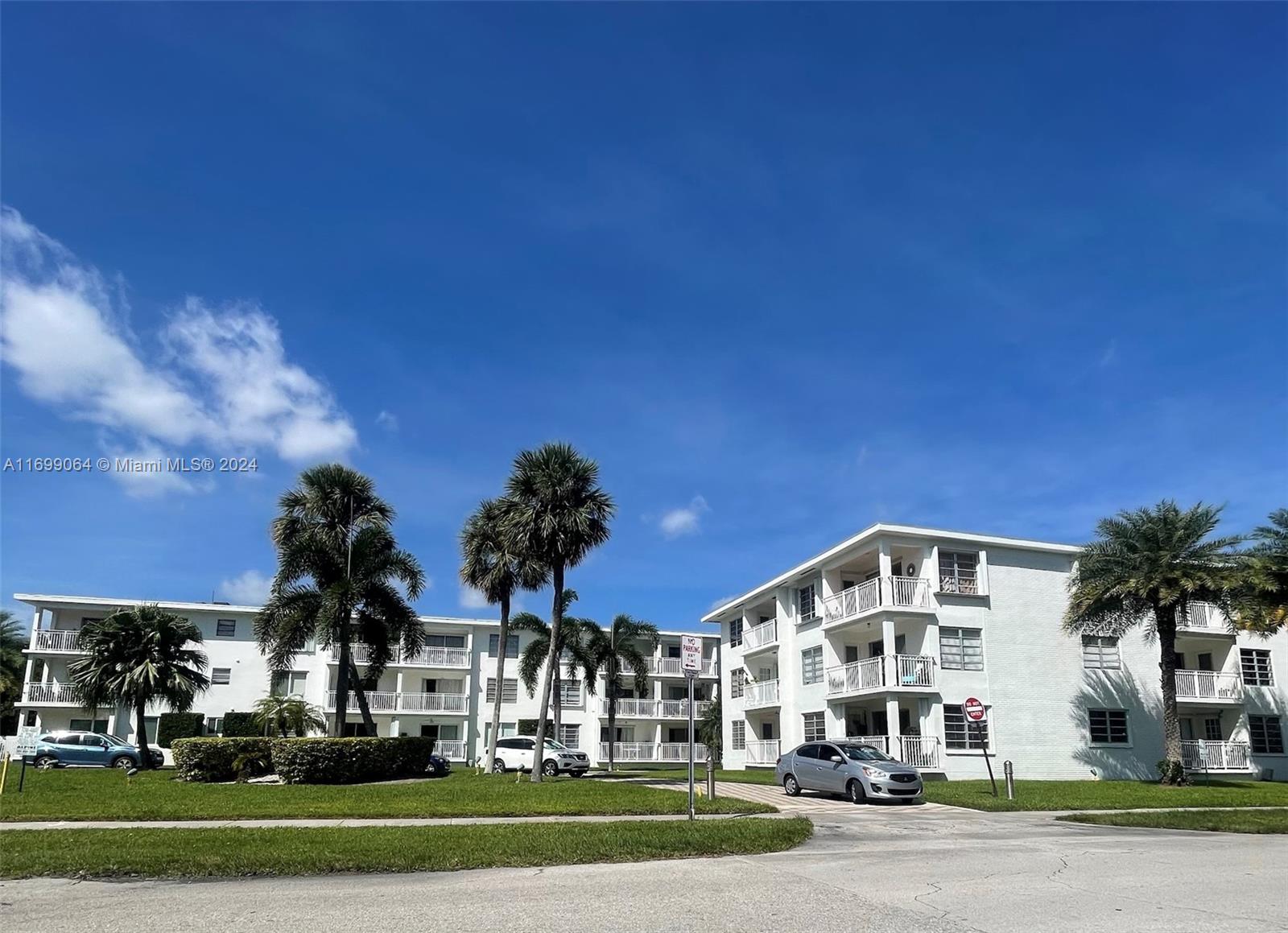 a front view of a building with streets and trees