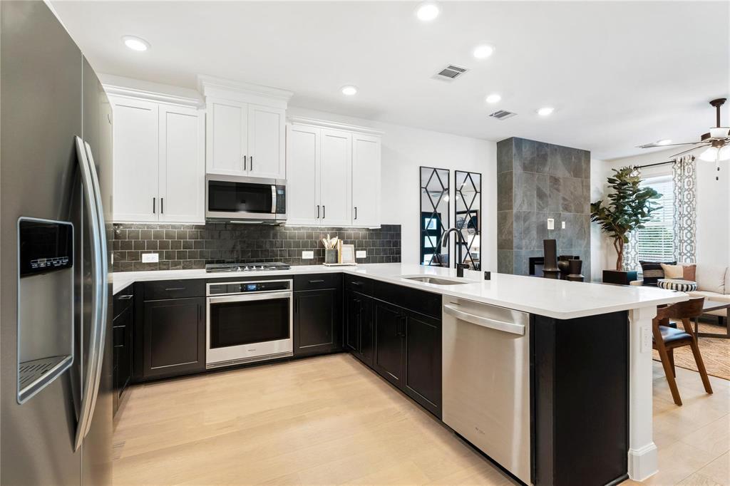 a kitchen with stainless steel appliances granite countertop a stove top oven a sink a refrigerator and white cabinets