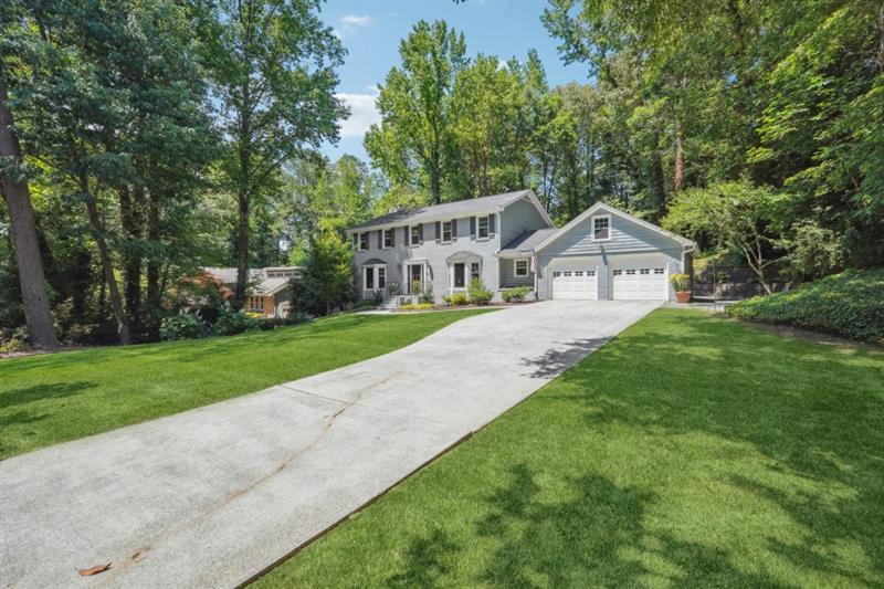 a view of house with a big yard and large trees