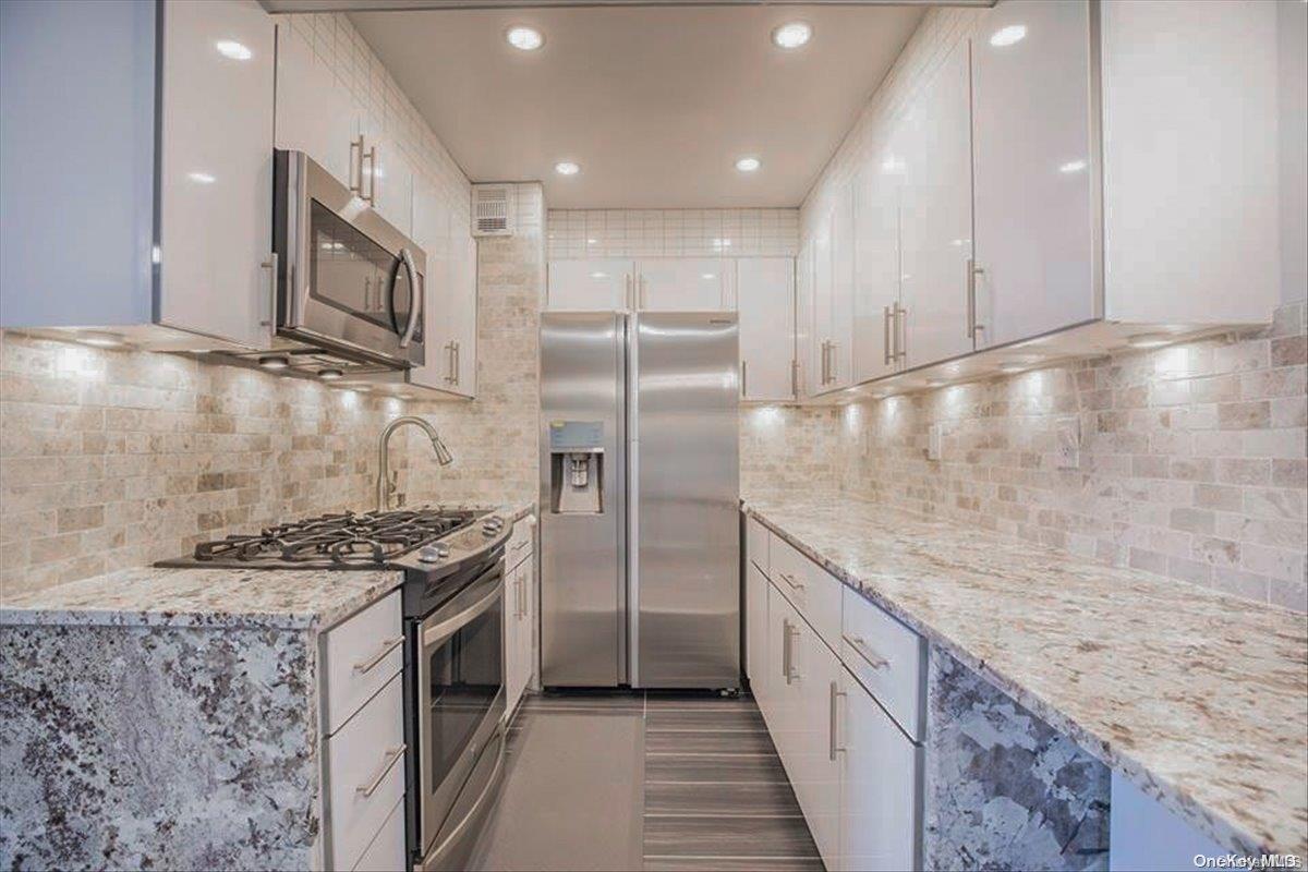 a kitchen with stainless steel appliances granite countertop a stove a sink and a refrigerator