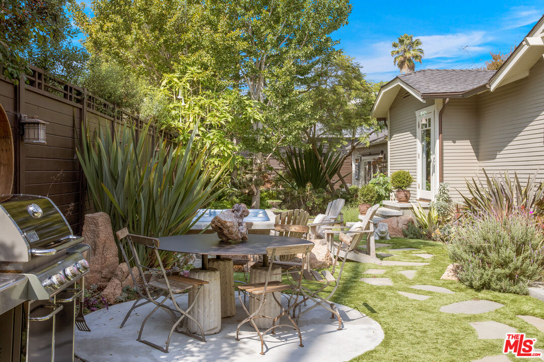 a view of a patio with table and chairs potted plants and large tree