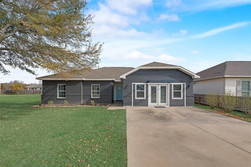 a front view of a house with yard and tree