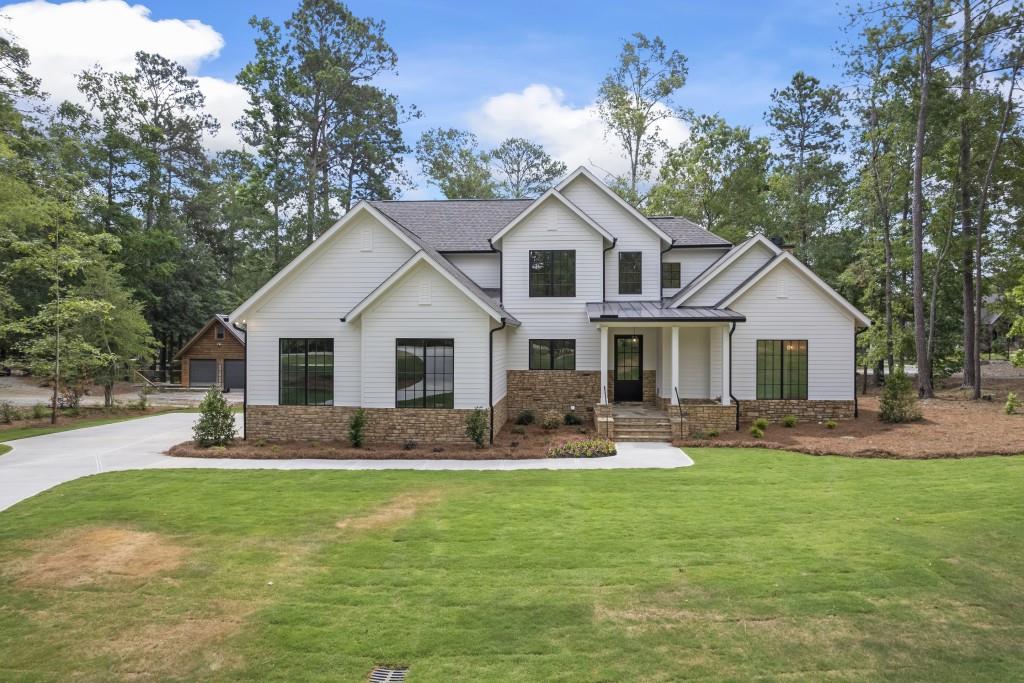 a front view of house with yard outdoor seating and covered with trees