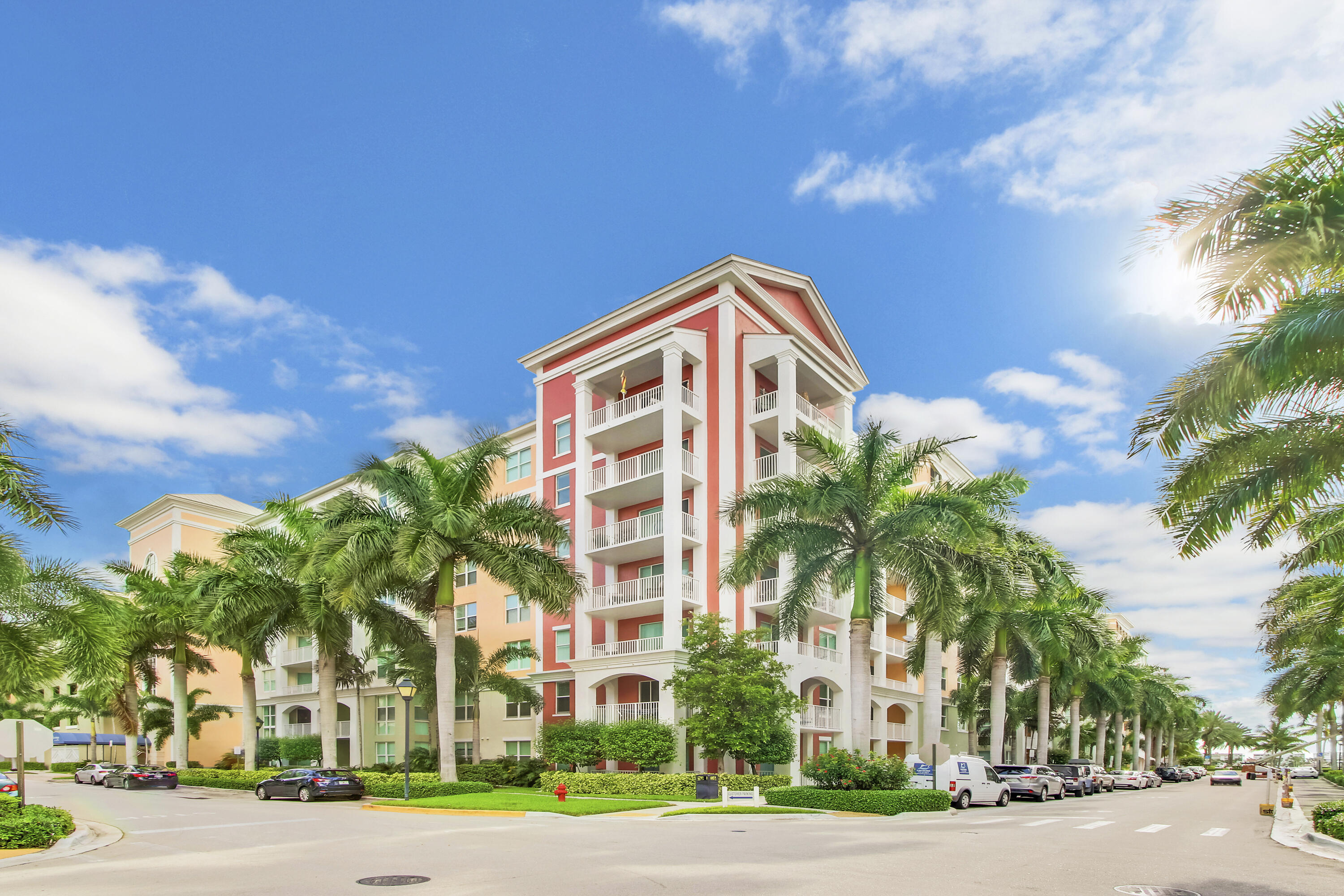 a front view of multi story residential apartment building with yard and traffic signal