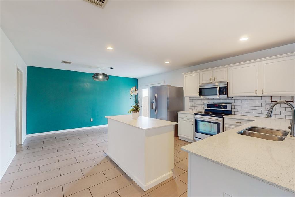 Kitchen featuring quartz, white cabinets, a kitchen island, and appliances with stainless steel finishes