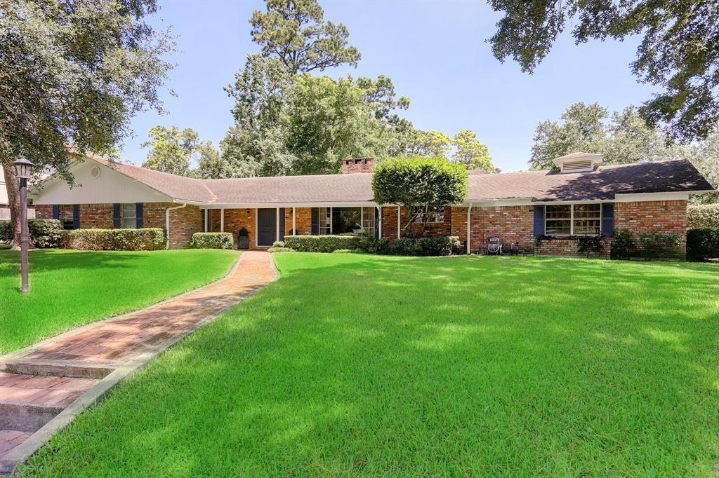 a view of a house next to a big yard and large trees