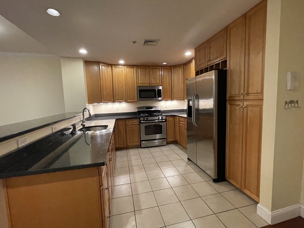 a kitchen with stainless steel appliances granite countertop a refrigerator and a stove top oven