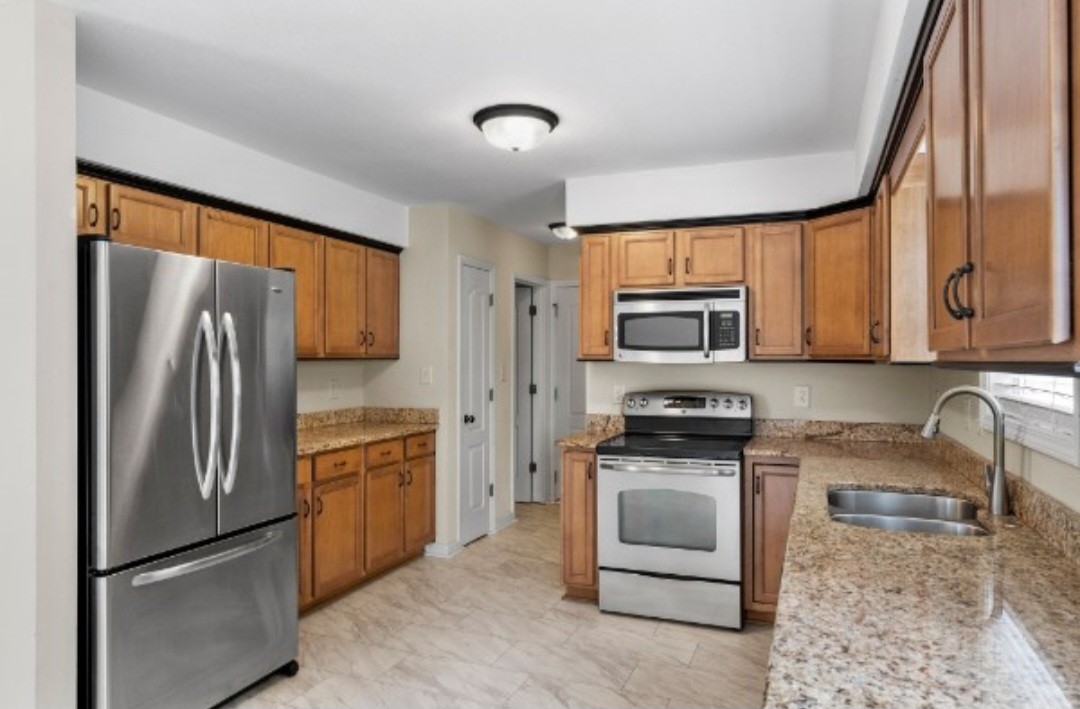 a kitchen with stainless steel appliances granite countertop a refrigerator stove and sink