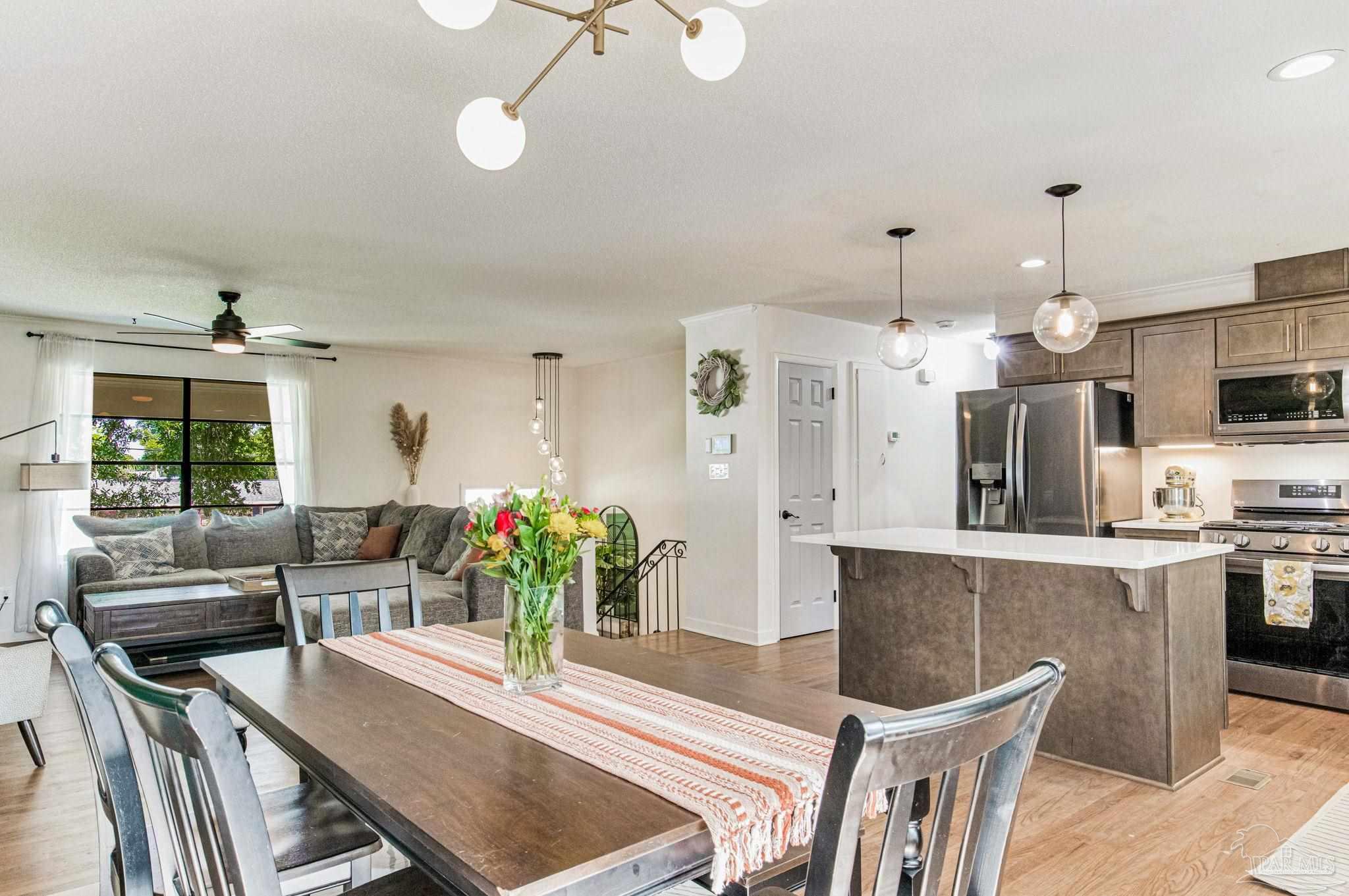 a kitchen with stainless steel appliances kitchen island granite countertop a table chairs in it and wooden floors