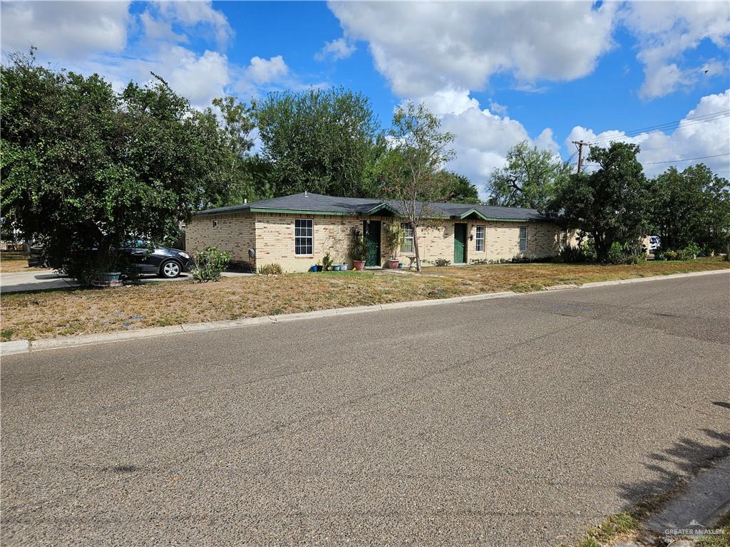 front view of house with yard and trees in the background