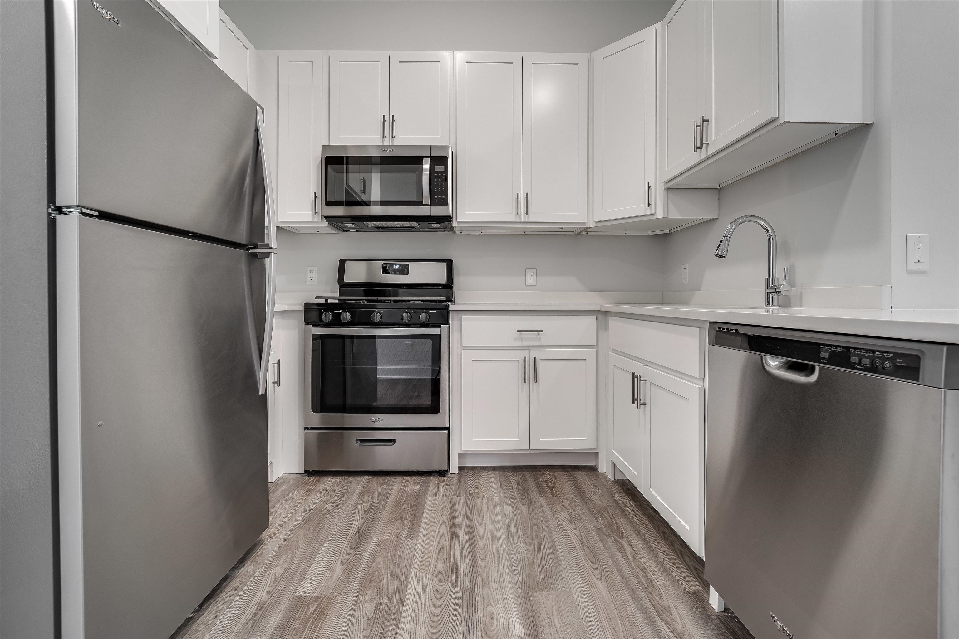 a kitchen with a sink stainless steel appliances and white cabinets