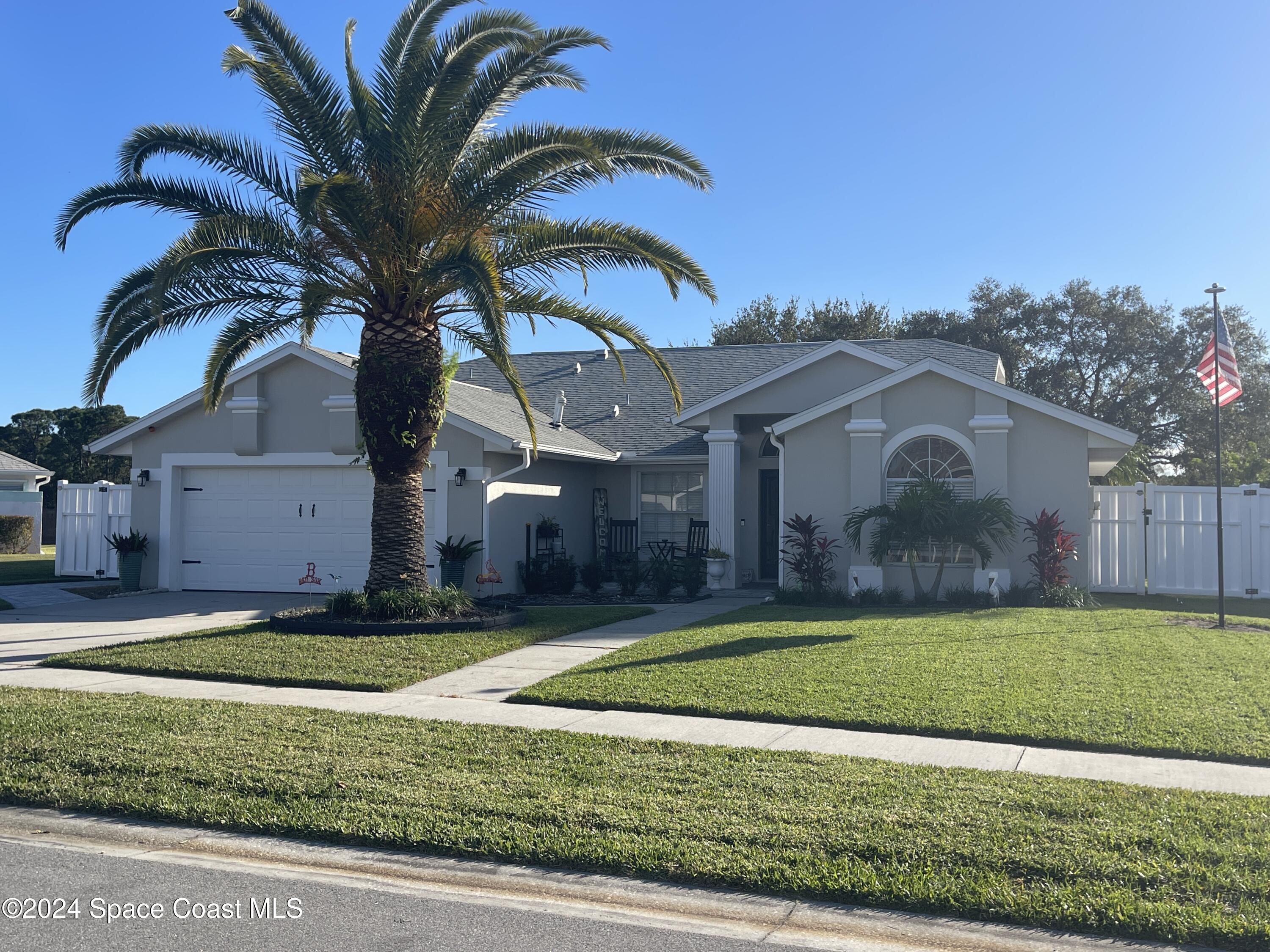 a view of a house with a yard and palm trees