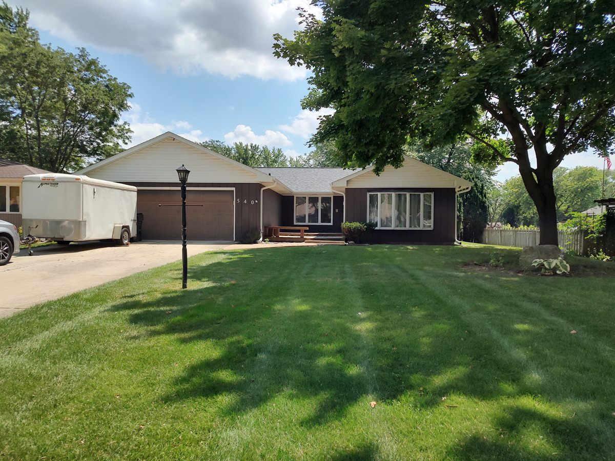 a front view of a house with a yard and trees