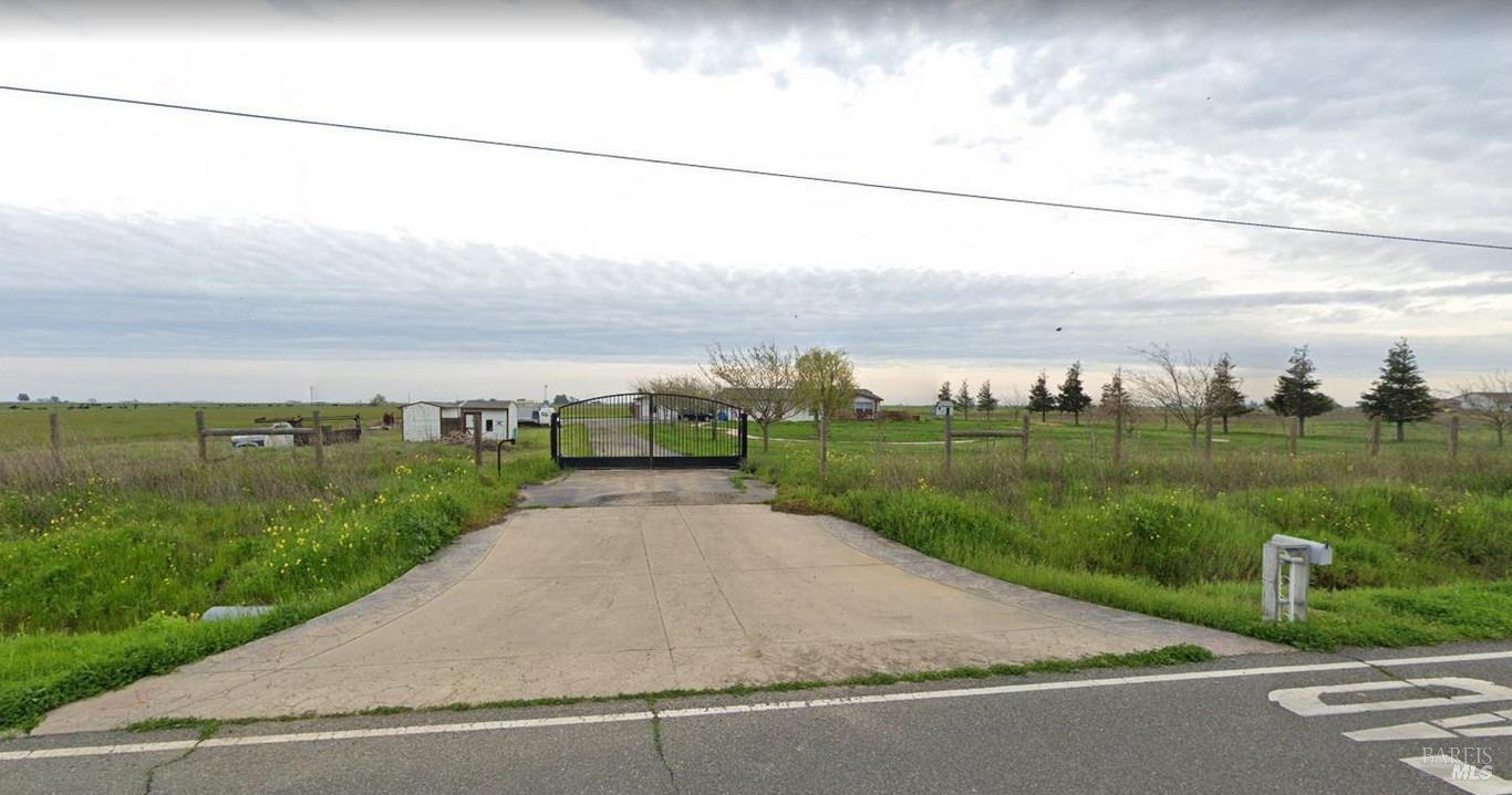 a view of a street with a yard and a wooden fence