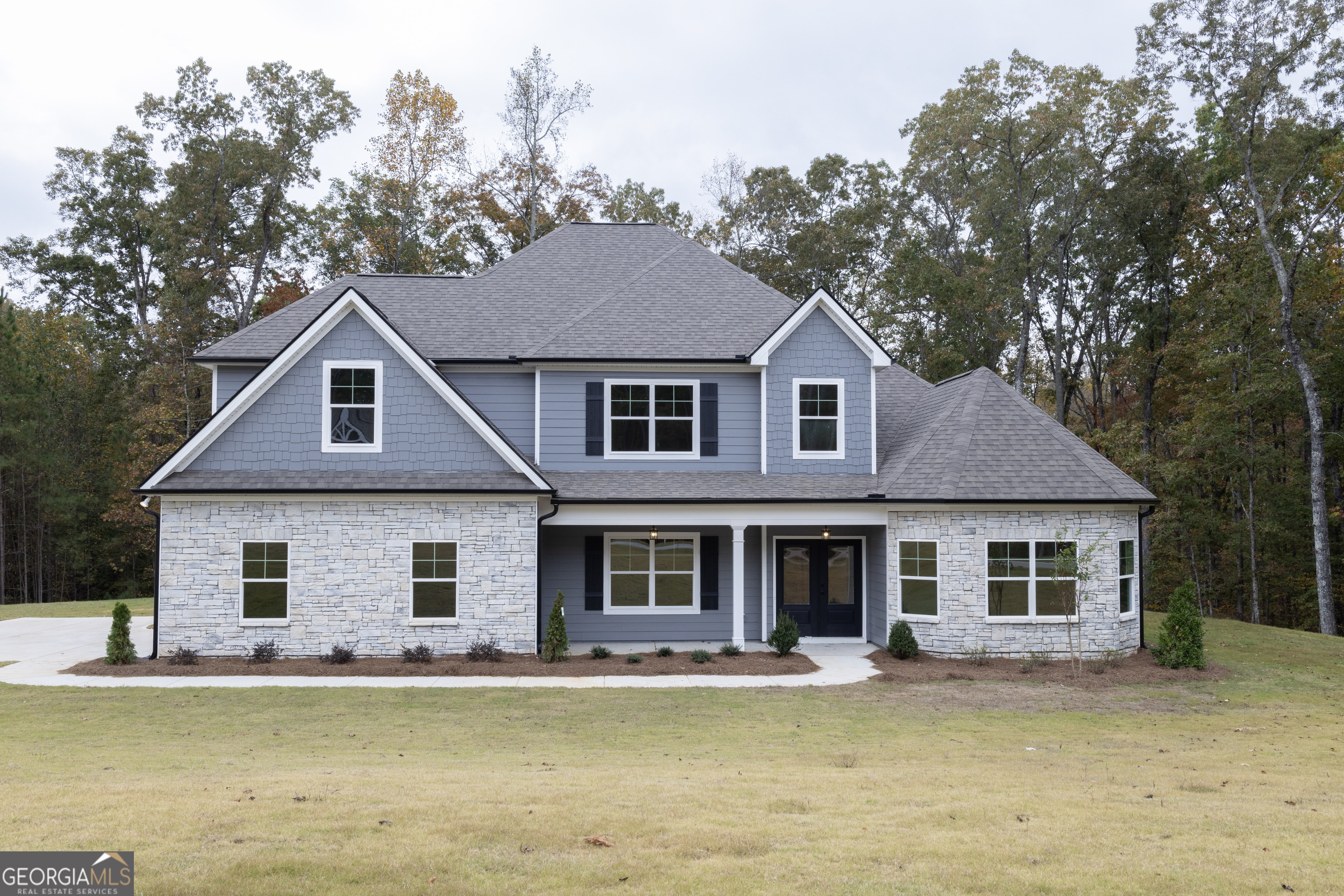 a front view of a house with a garden and lake view