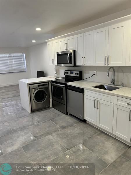 a kitchen with a sink white cabinets and stainless steel appliances