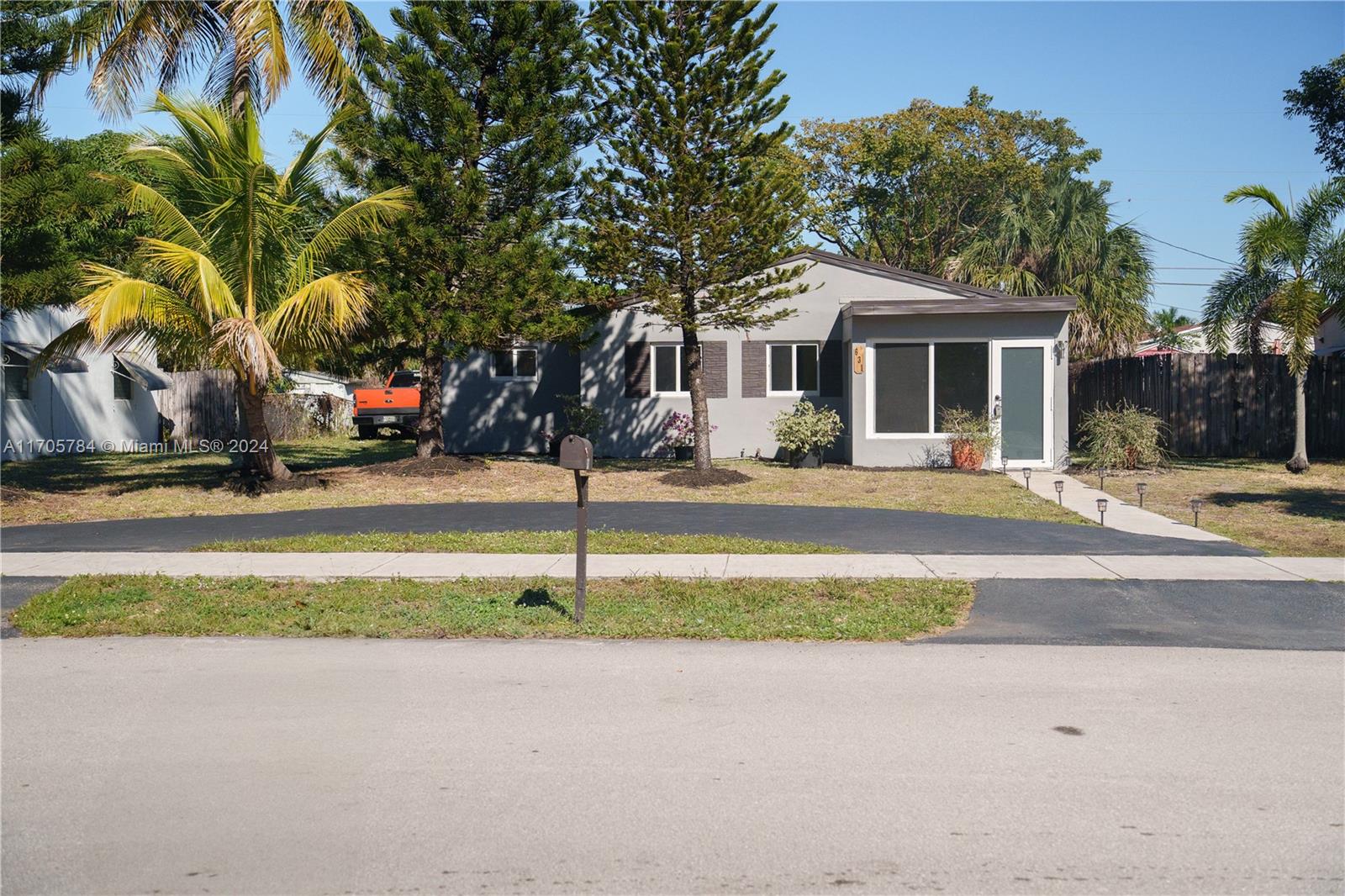 a front view of a house with a yard and palm trees