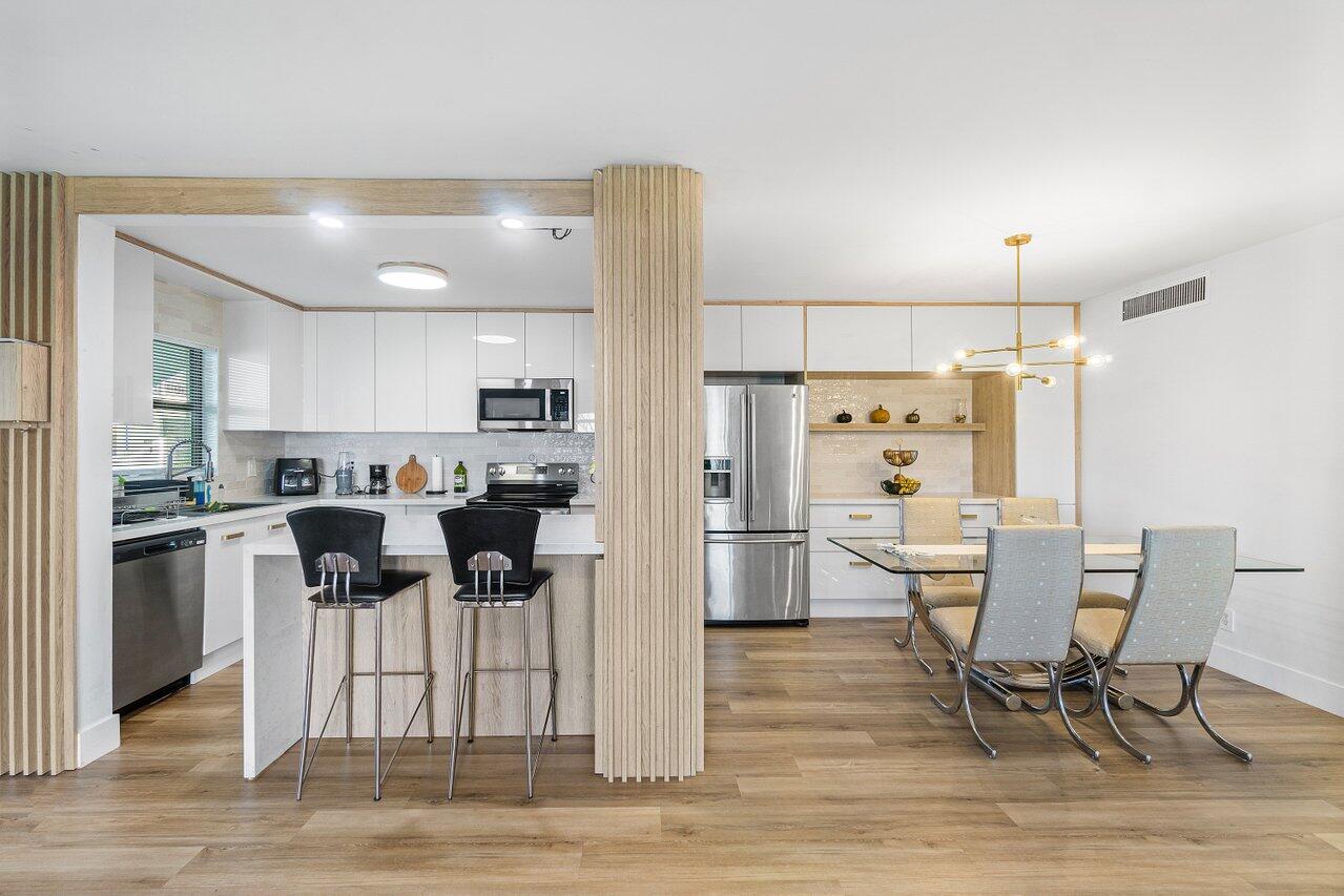 a kitchen with stainless steel appliances kitchen island granite countertop a table chairs and a refrigerator