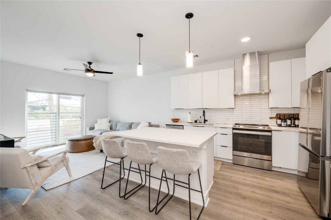 a kitchen with stainless steel appliances a stove a sink a oven a table and chairs