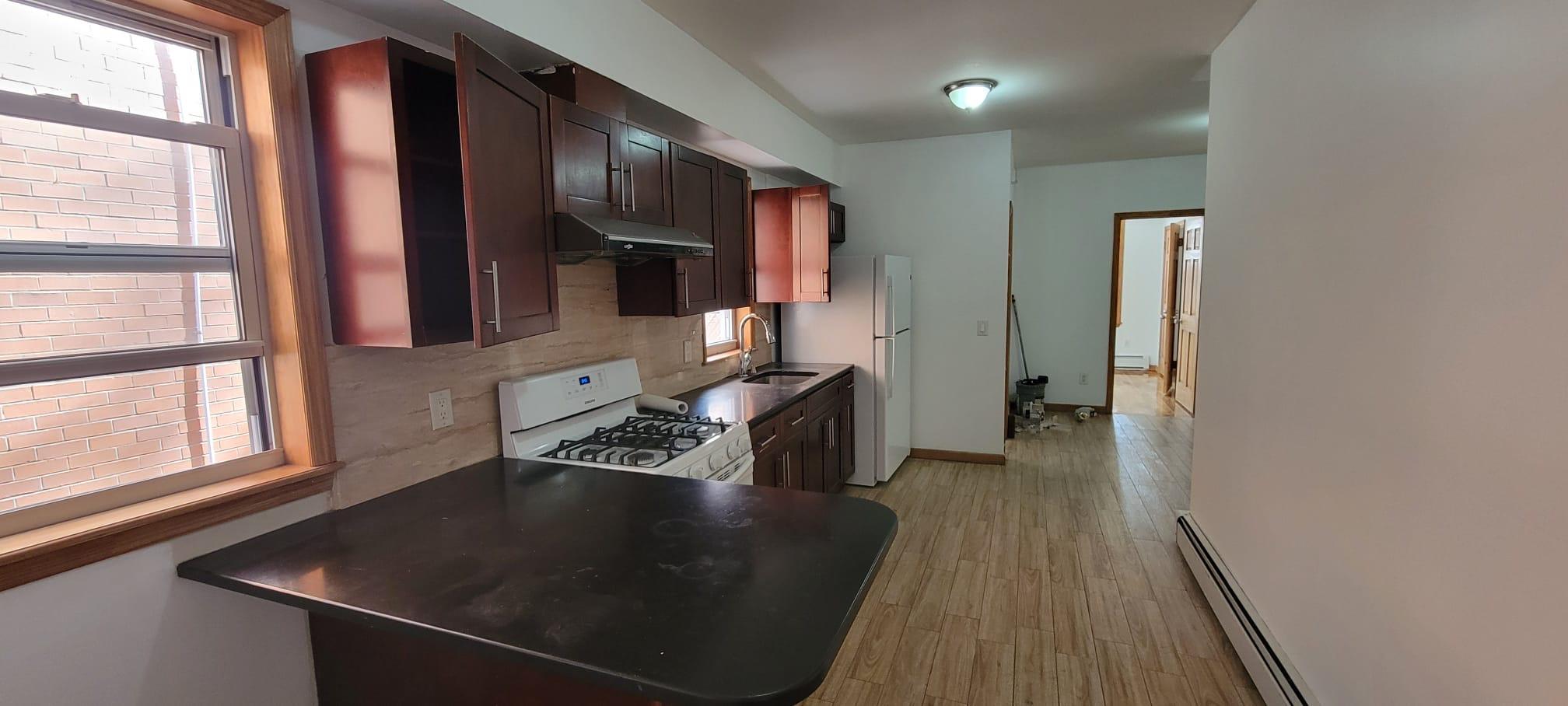 Kitchen with white appliances, a baseboard radiator, light hardwood / wood-style flooring, and sink