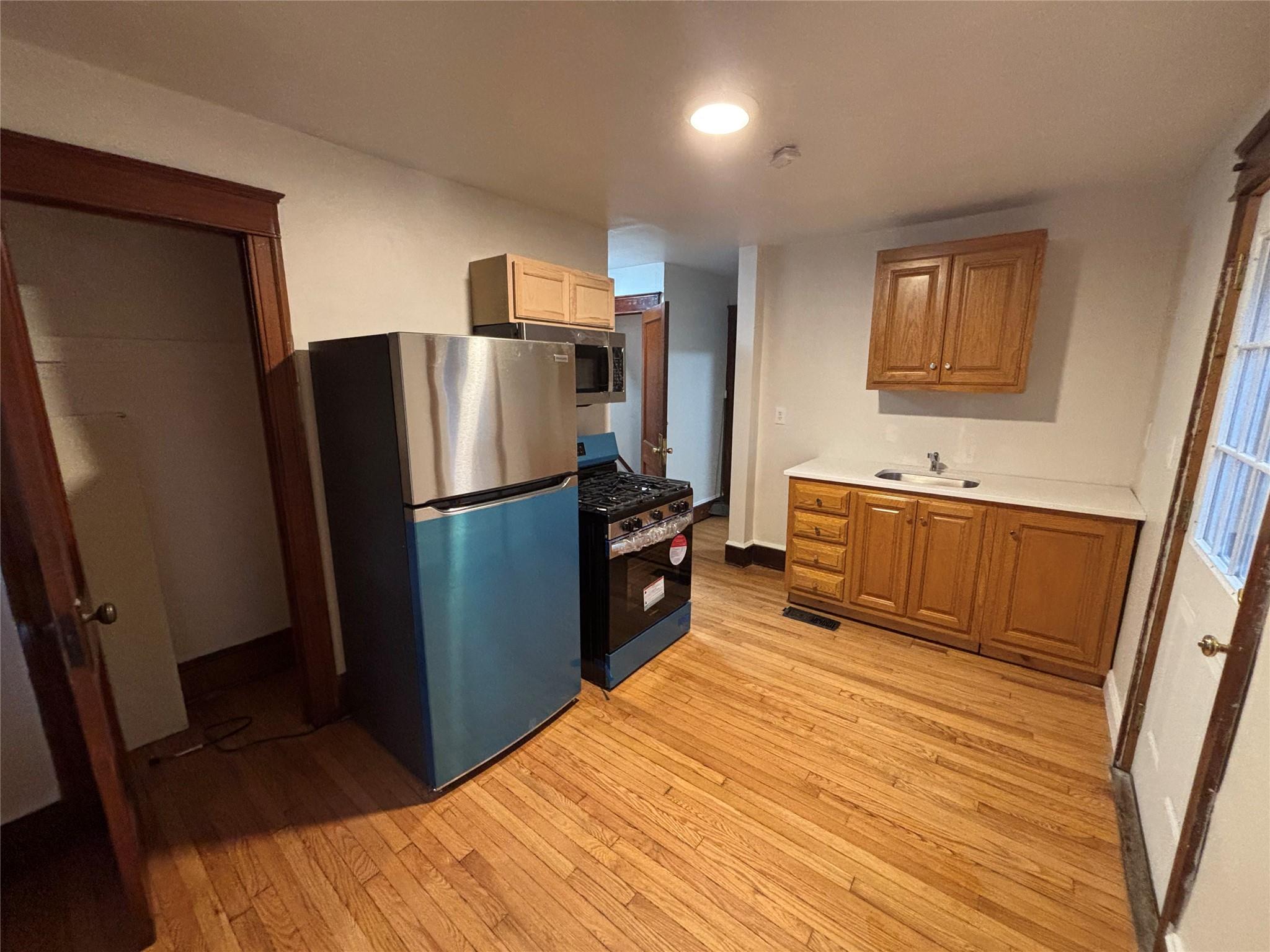 Kitchen with sink, light hardwood / wood-style flooring, and appliances with stainless steel finishes