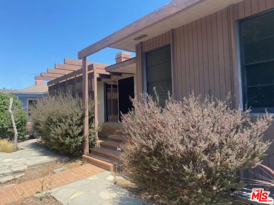 a view of a house with a yard and potted plants