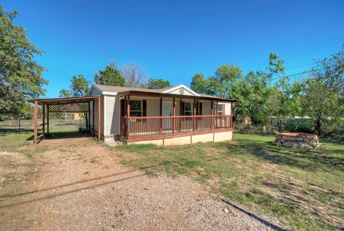 Welcome home to 14704 Running Deer Trail. Front of the home with the carport on the left and the fire pit to the right of the covered porch.