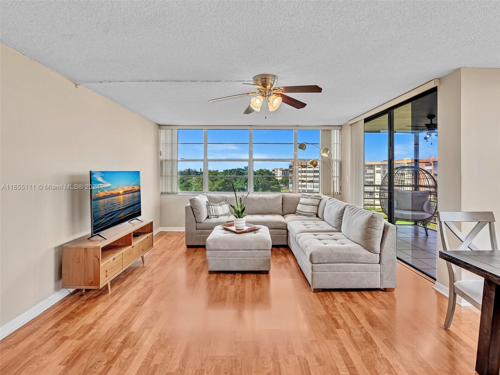 a living room with furniture a flat screen tv and a large window