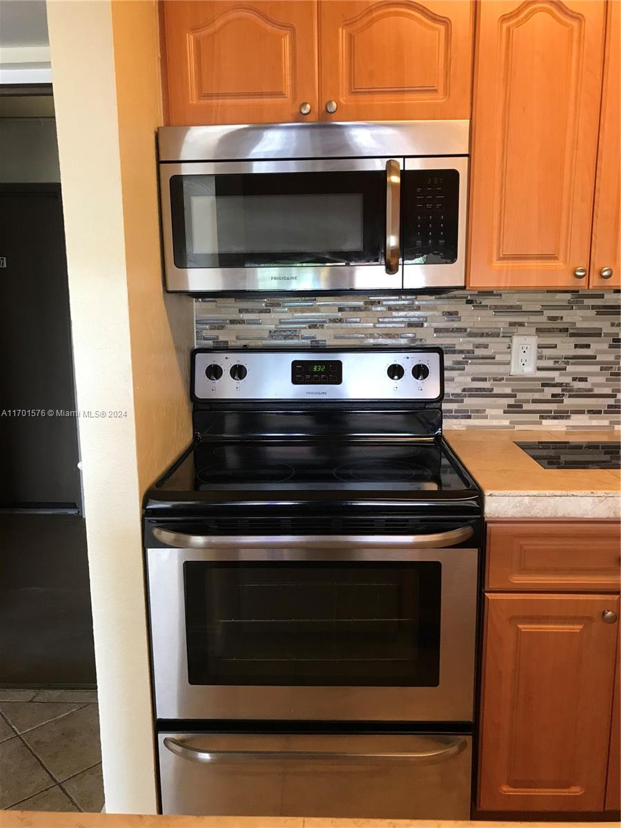 a stove top oven sitting inside of a kitchen with stainless steel appliances wooden floor