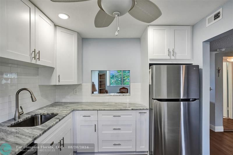 a kitchen with granite countertop a refrigerator and a sink