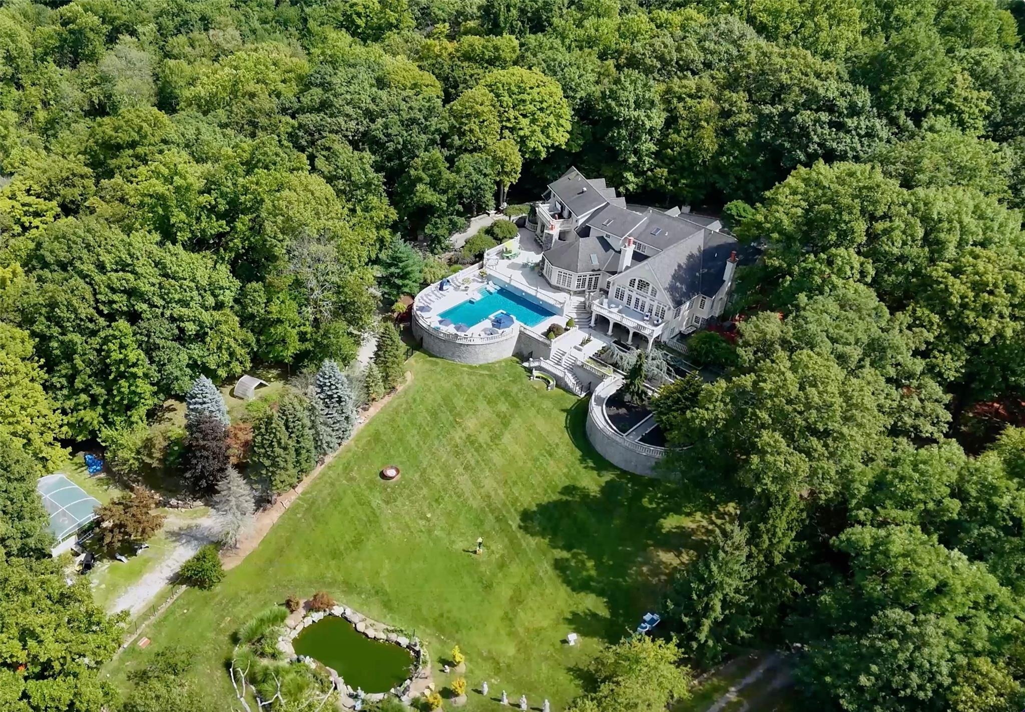 an aerial view of residential house with outdoor space and trees all around