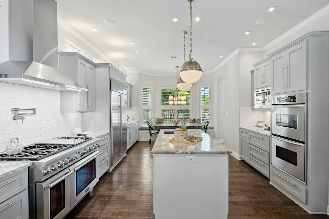 a kitchen with stainless steel appliances a stove a sink and white cabinets with wooden floor