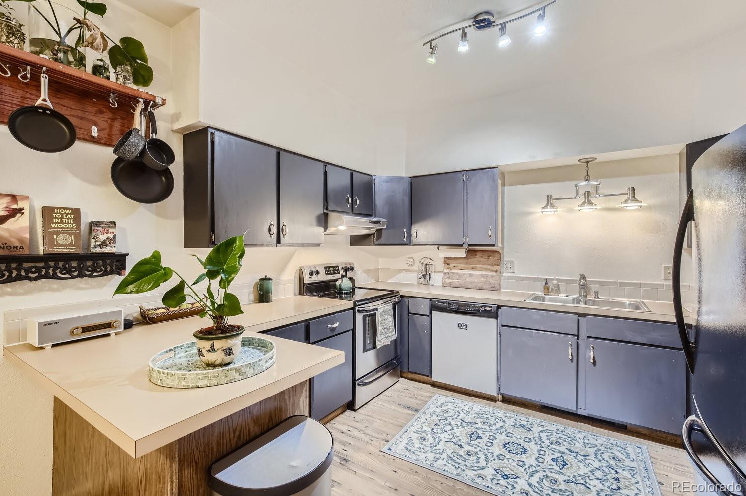 a kitchen with a sink a stove and chairs with wooden floor