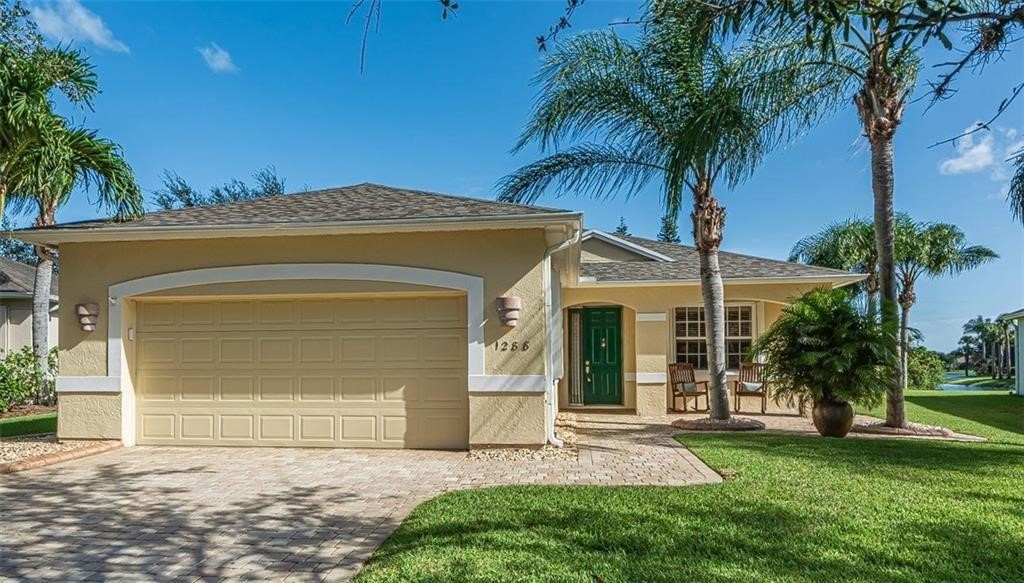 front view of house with a yard and palm trees