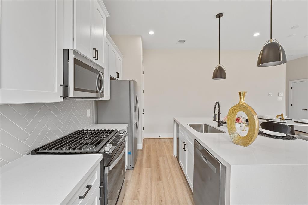 a kitchen with stainless steel appliances granite countertop a sink a stove and a wooden floors