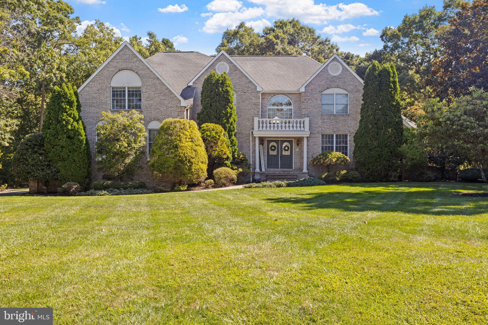 a view of a big house with a big yard and large trees