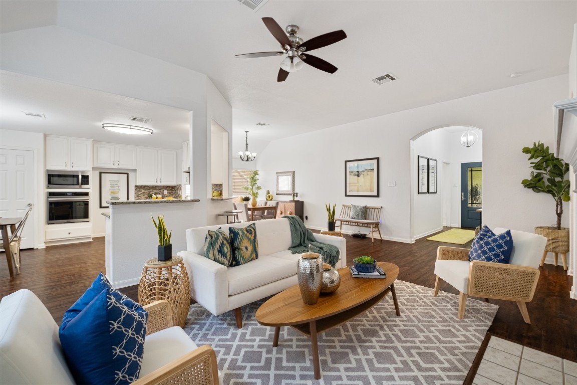 a living room with furniture kitchen view and a chandelier