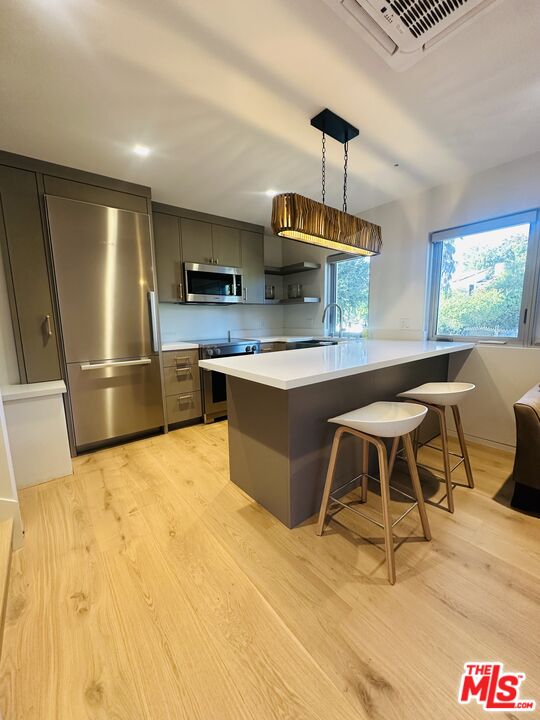 a kitchen with stainless steel appliances kitchen island a table chairs in it and wooden floors