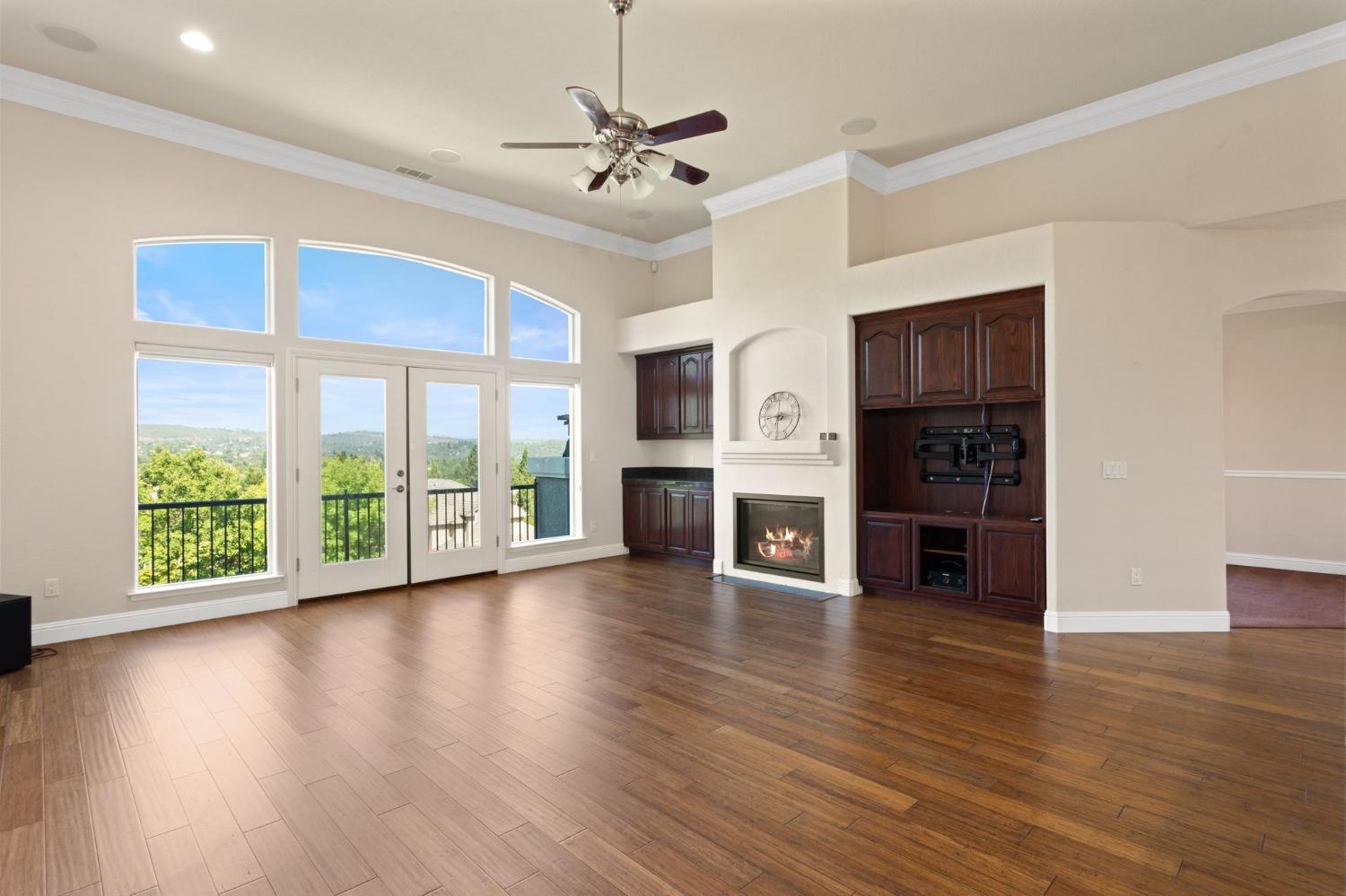 a view of an empty room with wooden floor fireplace and a window