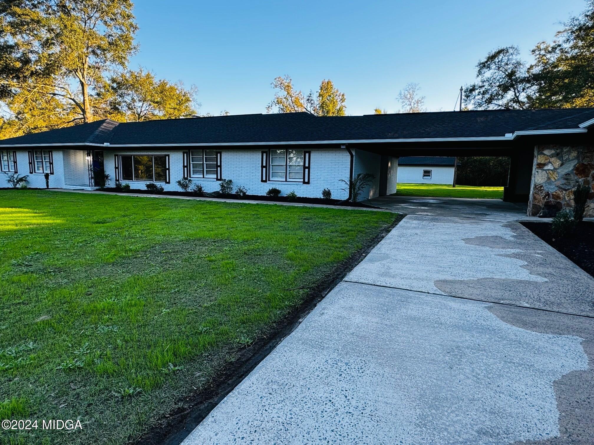 a view of a yard in front of a house with large windows