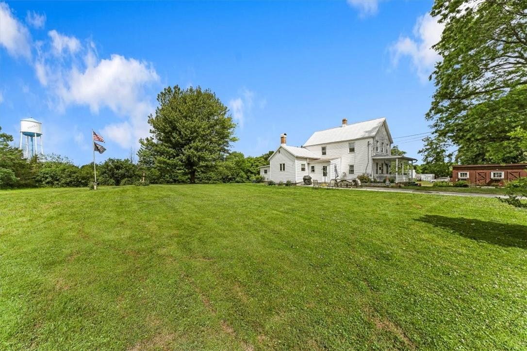 a white house with a big yard and large trees