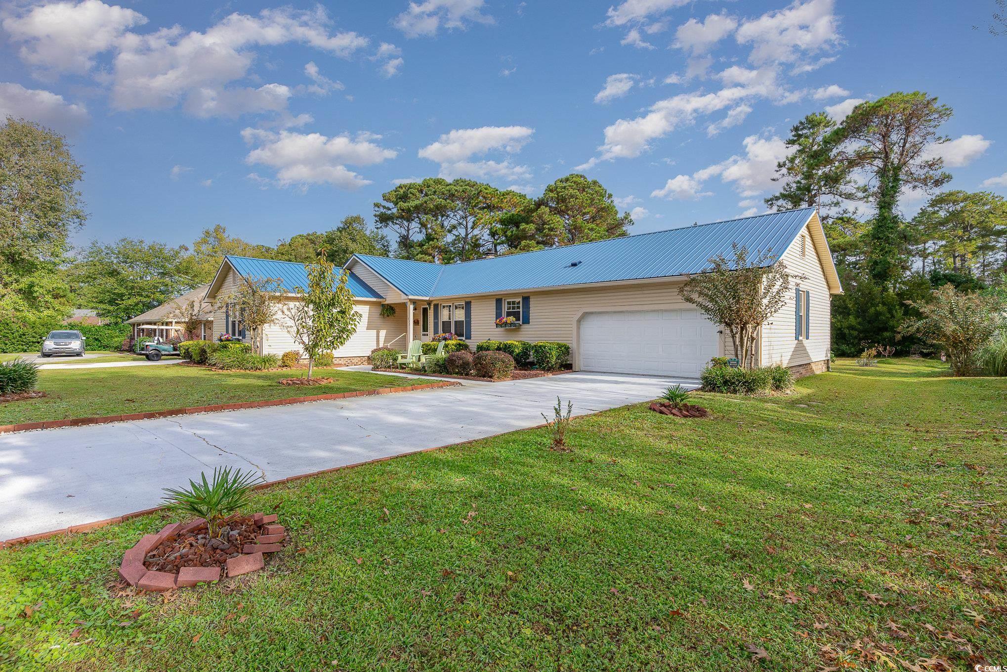 Ranch-style home featuring a front yard and a gara