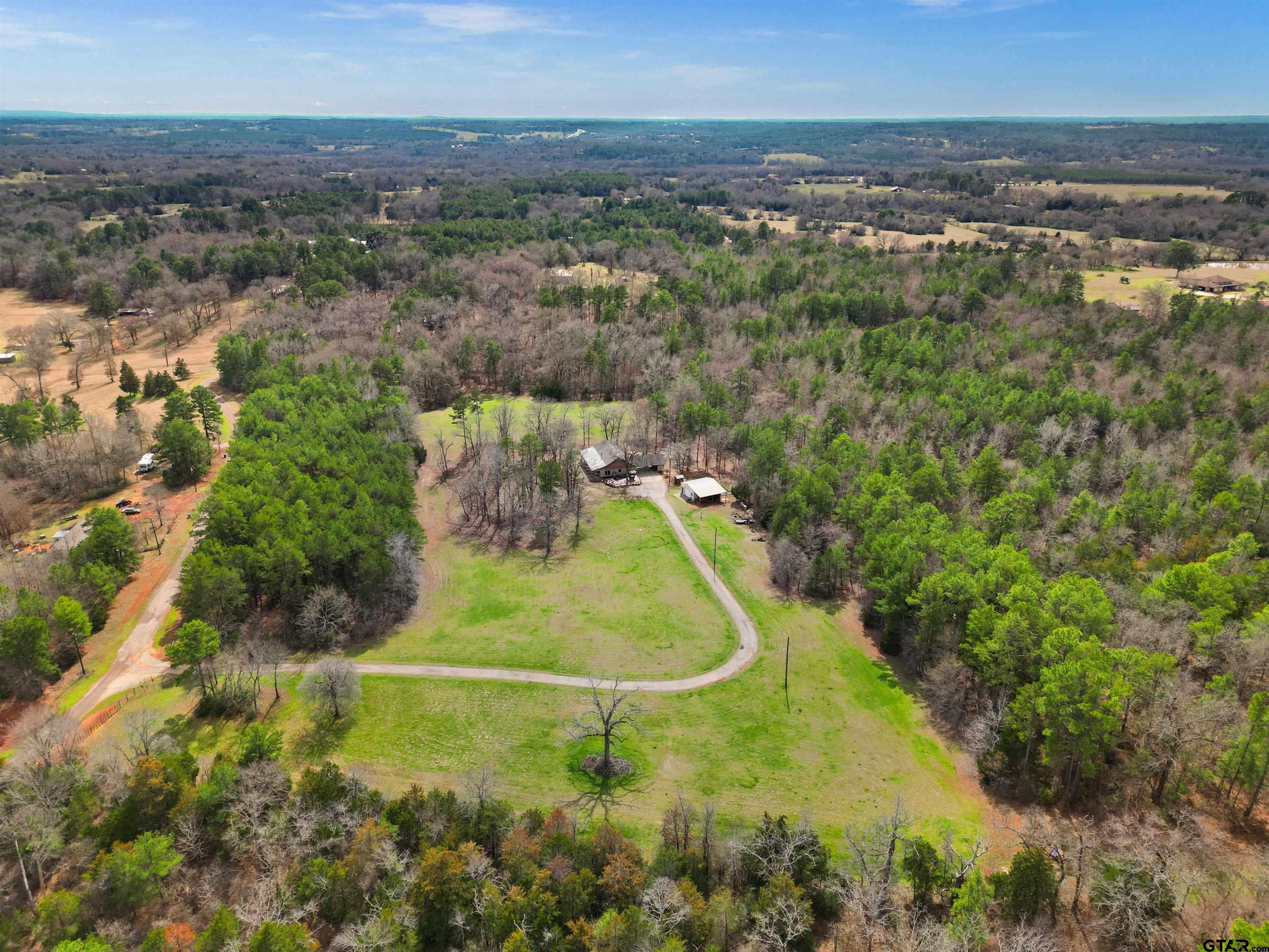 an aerial view of a residential houses with outdoor space and trees